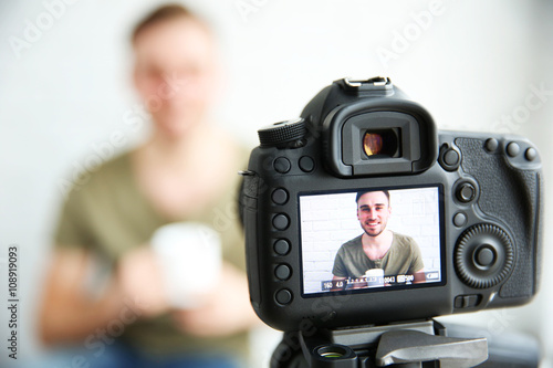 Young male blogger with cup of tea on camera screen © Africa Studio