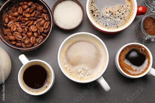 Different types of coffee in cups on dark table, top view