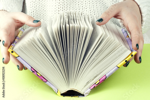 Young girle reading an  open book . old book. Books and reading are essential for self improvement, gaining knowledge and success in our careers, business and personal lives.