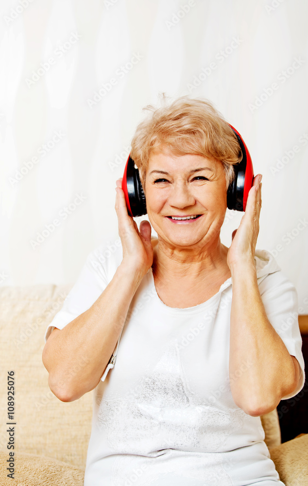 Naklejka premium Happy senior woman wearing red headphones 