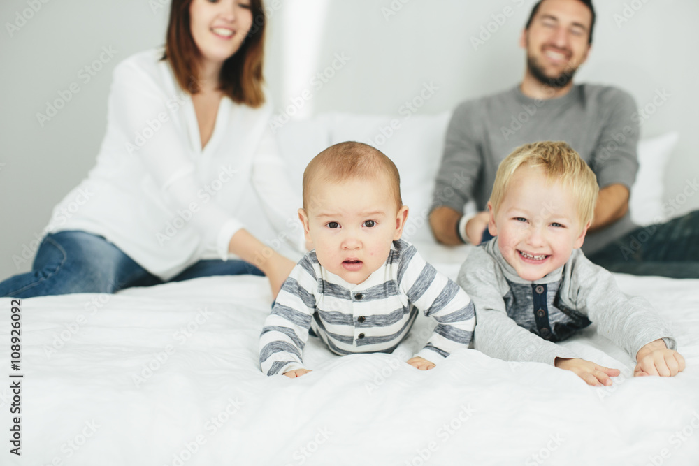 Parents with two small kids playing in bedroom Parents with two small kids playing in bedroom