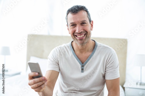 Man using smartphone in bedroom