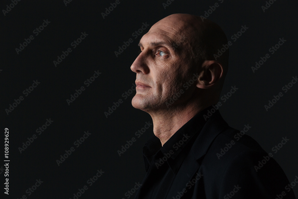Fototapeta premium Profile of attractive boldheaded businessman in dark suit