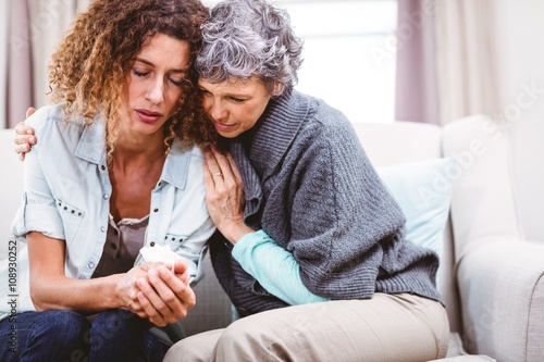 Foto Mother comforting tensed daughter sitting on sofa