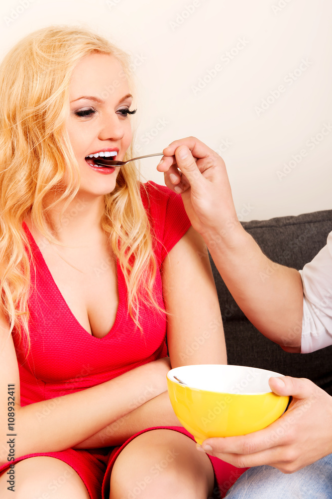 Man feeds his girlfriend on the sofa Man feeds his girlfriend on the sofa