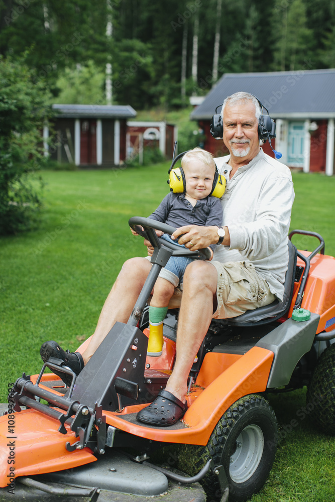 Grandfather with grandson on ride-on lawn mower Grandfather with grandson on ride-on lawn mower
