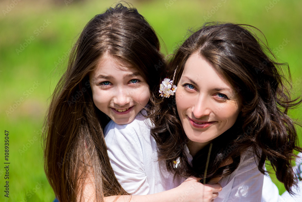 Daughter with the mother sitting on the grass and talking Daughter with the mother sitting on the grass and talking