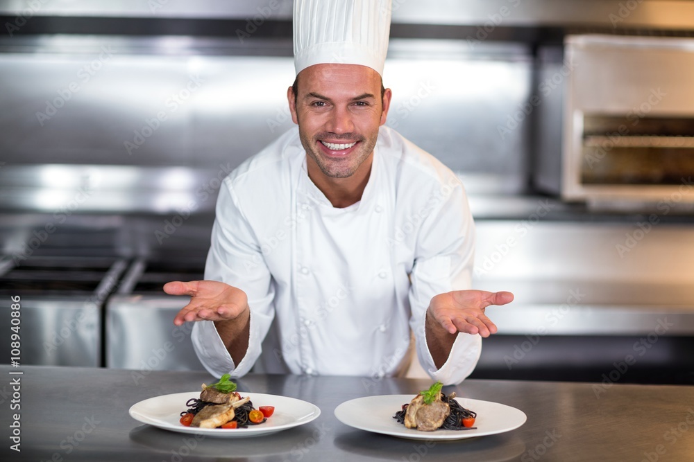 Portrait of smiling chef showing food plates in kitchen Portrait of smiling chef showing food plates in kitchen