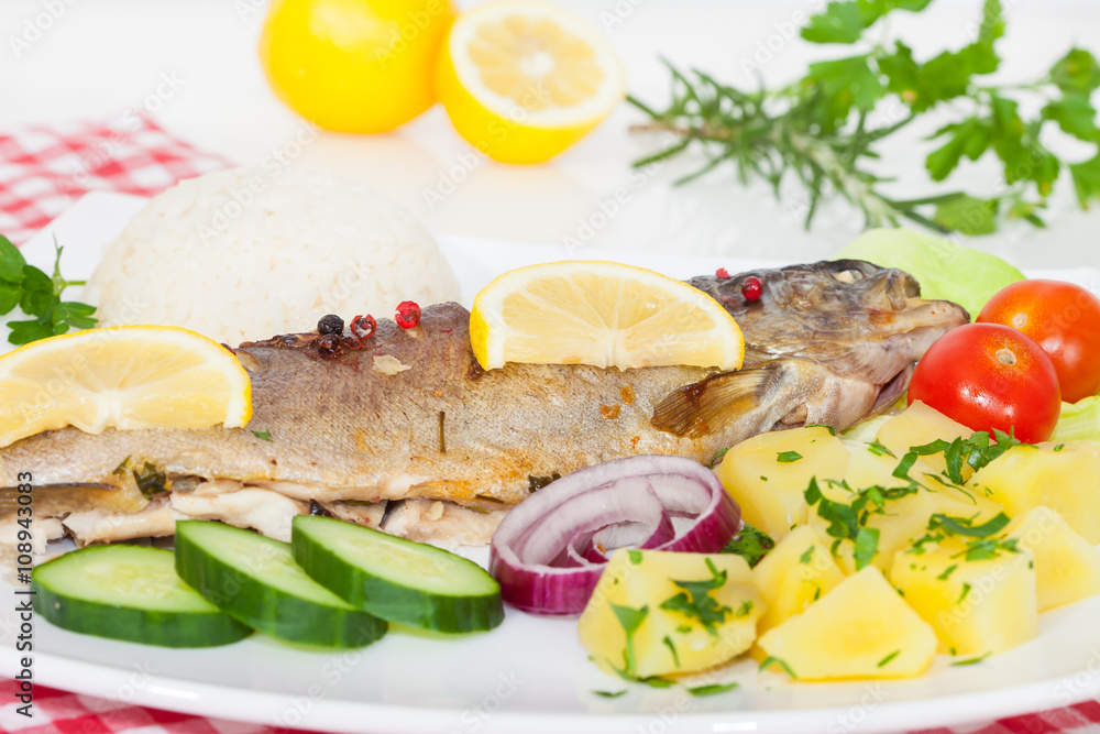 Trout fish baked with potatoes, lemon, spices and herbs Trout fish baked with potatoes, lemon, spices and herbs