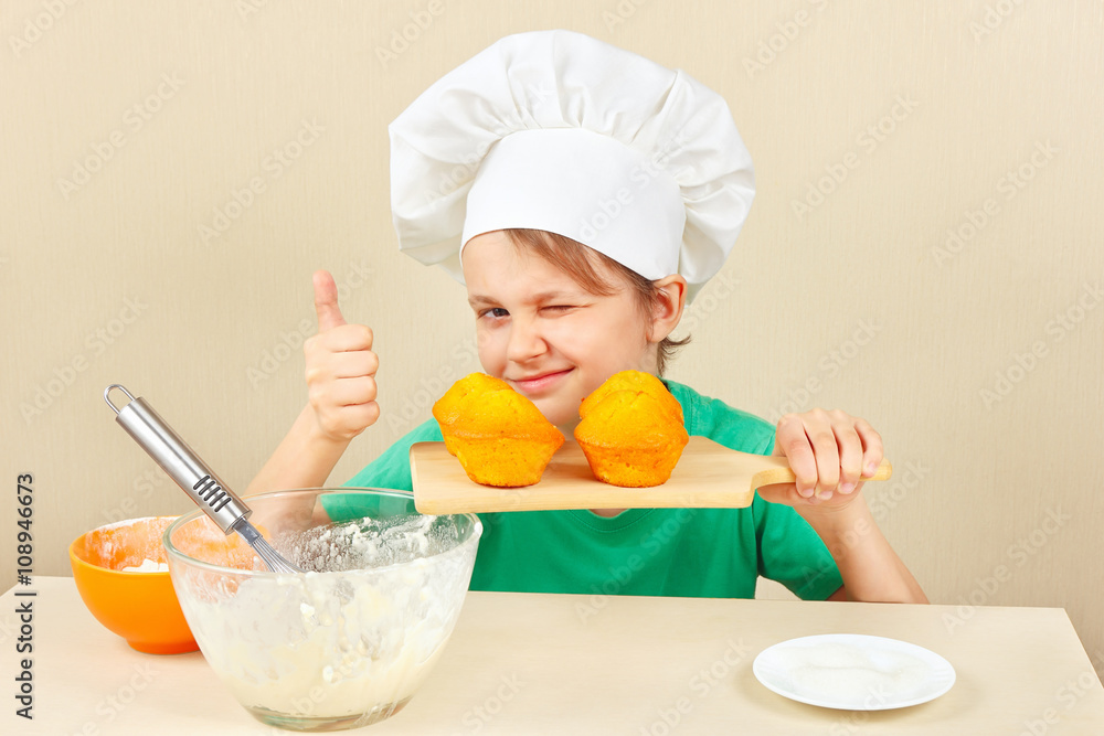 Little boy in chef hat with a cooked the appetizing muffin Little boy in chef hat with a cooked the appetizing muffin