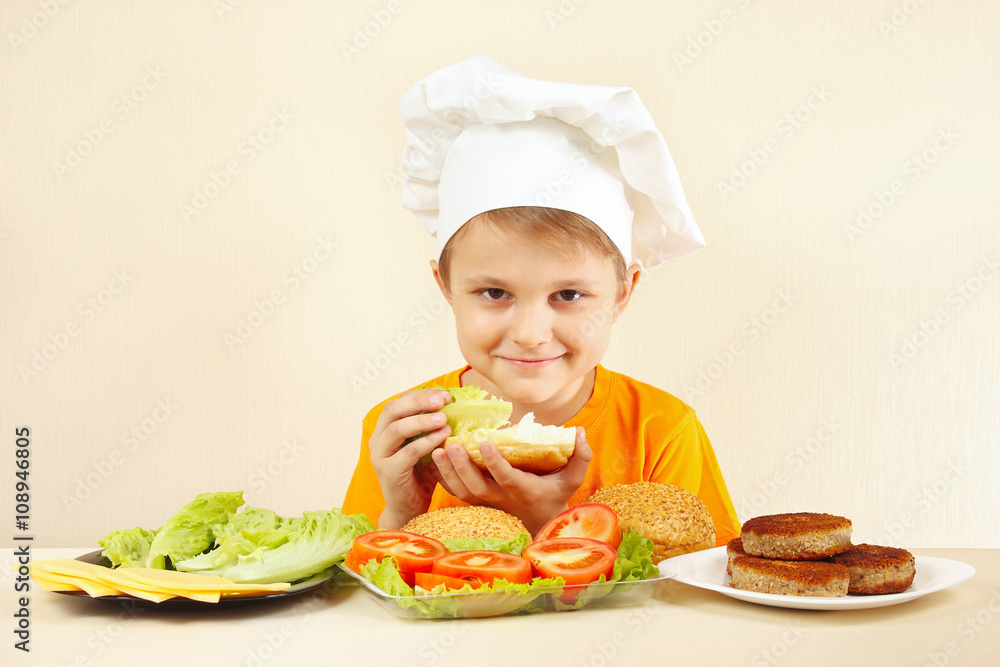 Young chef puts salad on the big sandwich Young chef puts salad on the big sandwich