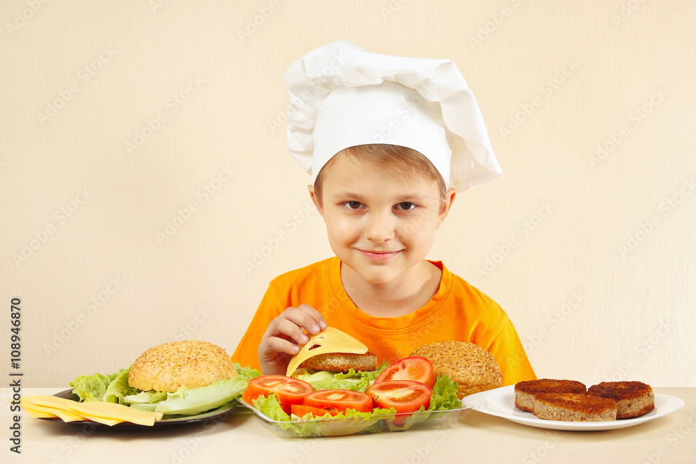 Little funny chef puts cheese on the hamburger Little funny chef puts cheese on the hamburger
