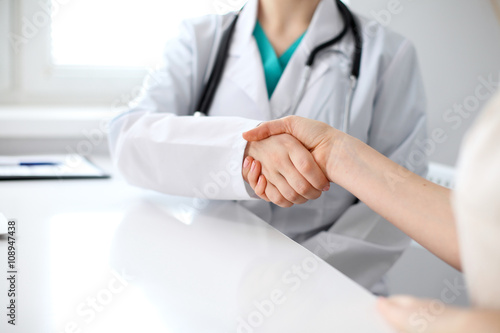 Handshake doctor and patient sitting at the table  closeup