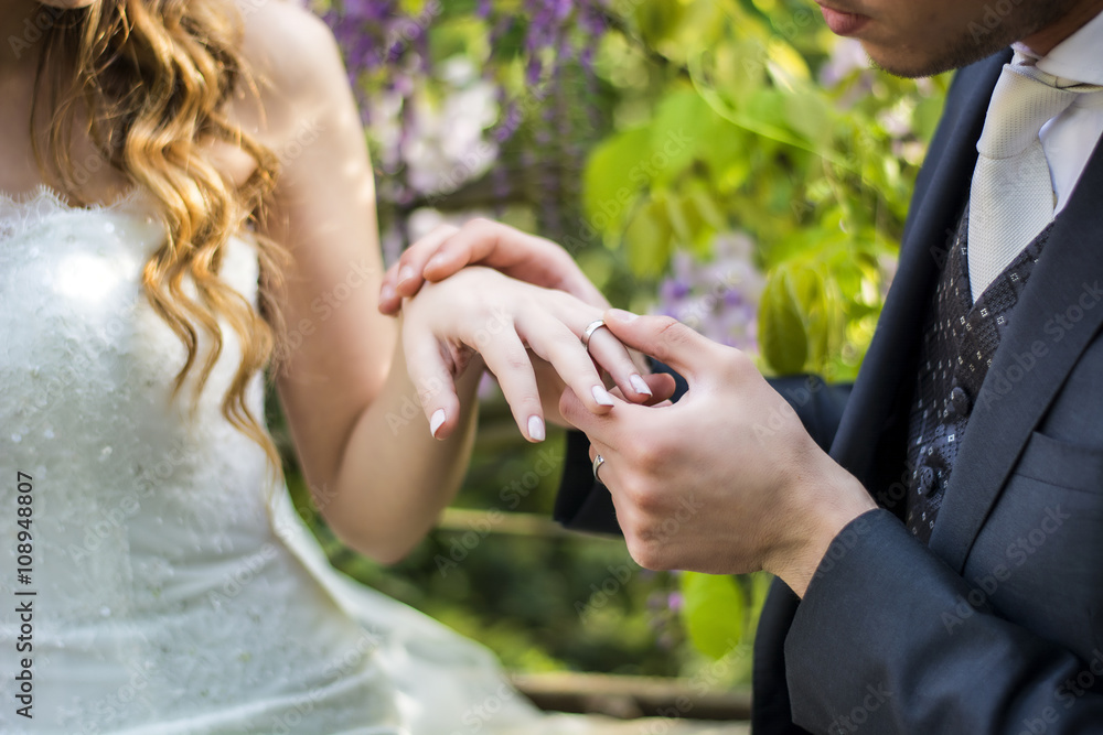 Close-up of bridegroom wearing wedding ring on bride's finger
