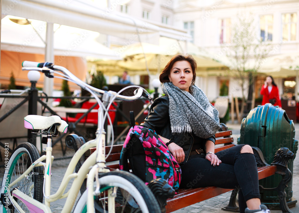 Obraz premium Girl with vintage bicycle sits thoughtfully in old town square