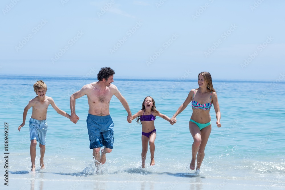 Family holding hands while running in shallow water