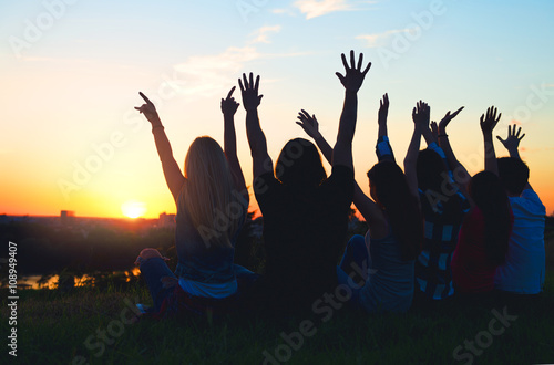 Group of people jumping outdoors; sunset 