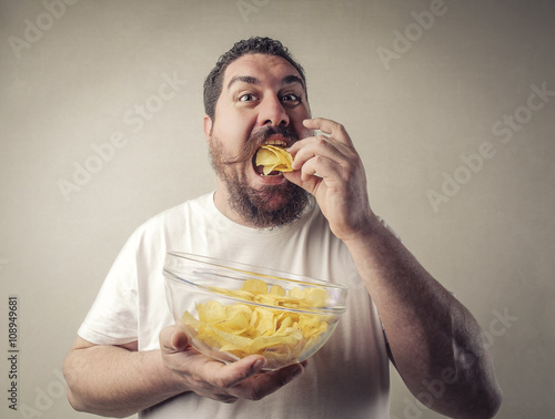 Fat man eating potato chips photo