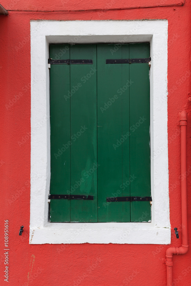 Old window with dark green shutters on red wall Old window with dark green shutters on red wall