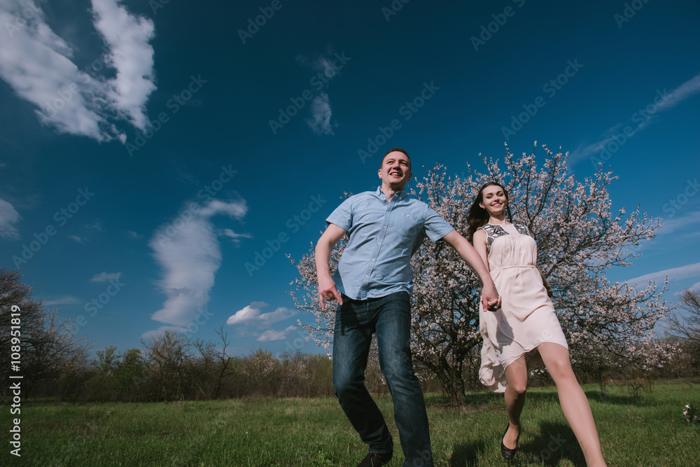 Happy couple running in bloom garden holding hand in hand on blue sky background,smile and have fun,lifestyle,yong