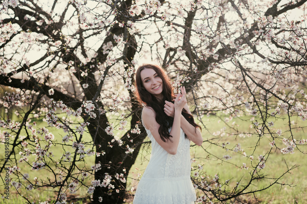 Beautiful brunette woman in the park standing near the blossom tree on a warm summer day,lifestyle Beautiful brunette woman in the park standing near the blossom tree on a warm summer day,lifestyle