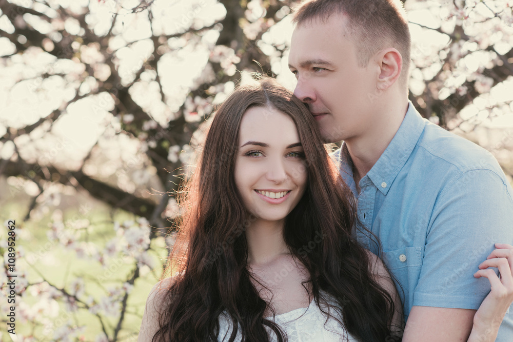 Young couple in love outdoor.Stunning sensual outdoor portrait of young stylish fashion couple posing in spring near blossom tree Young couple in love outdoor.Stunning sensual outdoor portrait of young stylish fashion couple posing in spring near blossom tree