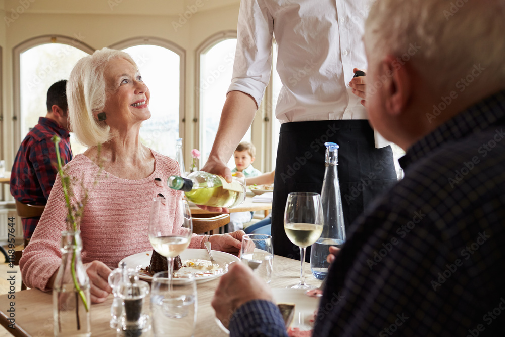 Waiter Serving Wine To Senior Couple In Restaurant Waiter Serving Wine To Senior Couple In Restaurant