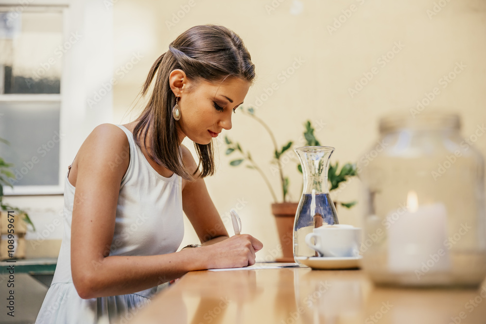 Austria, Vienna, Young woman sitting in Heurigen restaurant writing postcards Austria, Vienna, Young woman sitting in Heurigen restaurant writing postcards