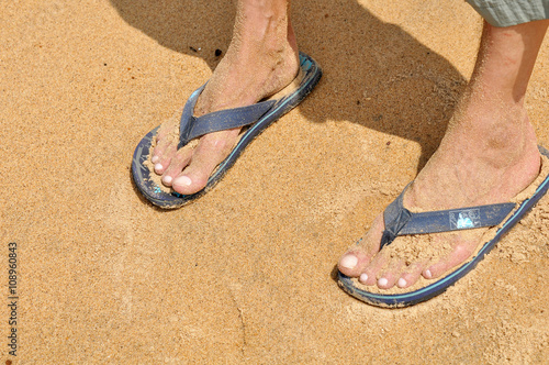 Men's foot in shales on the beach in