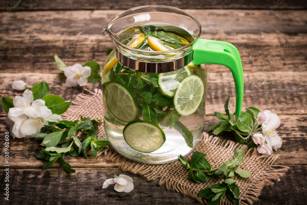 detox water with a lemon, lime and mint on a wooden table