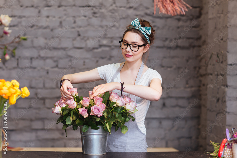 Beautiful woman florist arranging roses in bucket - obrazy, fototapety, plakaty 
