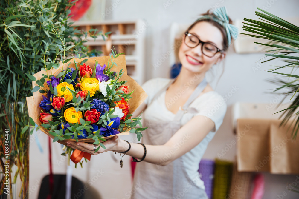 Cheerful woman florist showing bouquet of colorful flowers