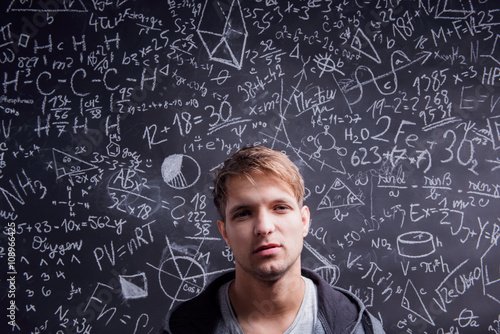 Student against a big blackboard with mathematical symbols © Halfpoint