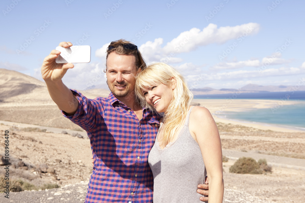 Spain, Fuerteventura, Jandia, couple taking selfie at the coast