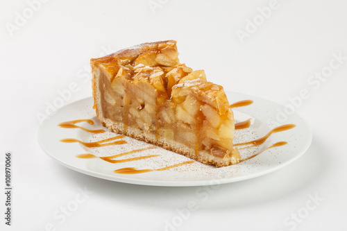 Delicious apple pie charlotte with caramel on the plate on white background. Close up side view.