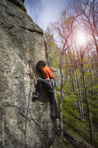 Athlete climbs on rock with rope.