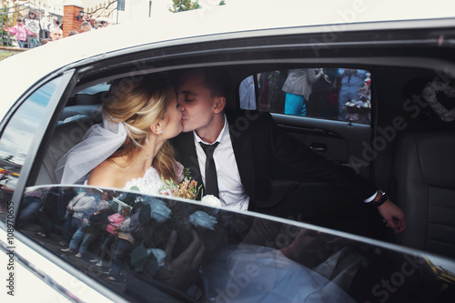 Happy romantic newlyweds kissing in wedding limo