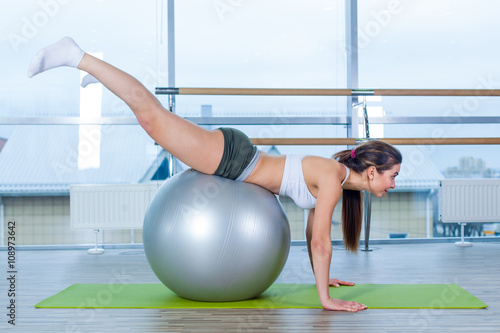 Young girl working out at the gym with a ball.
