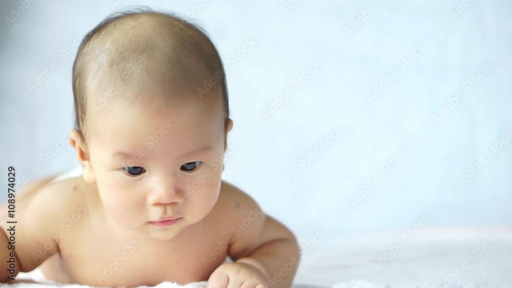 Asian baby lying on stomach and raising his head Asian baby lying on stomach and raising his head