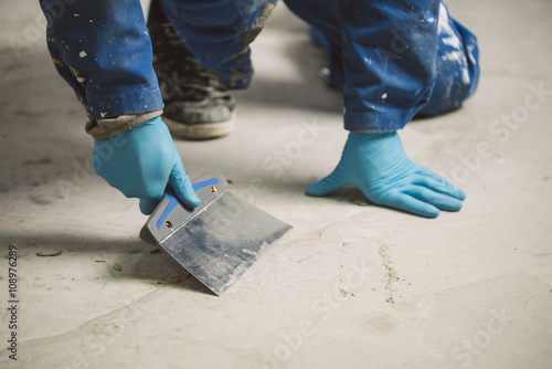 Bricklayer removing irregularities on floor screed with spatula photo