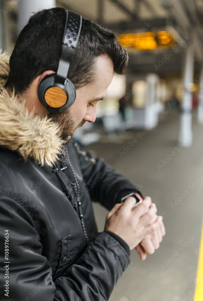 Man with headphones standing on platform using smartwatch Man with headphones standing on platform using smartwatch