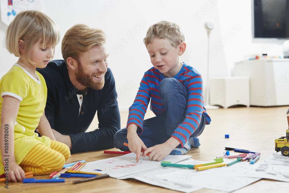 Father lying on floor with children painting