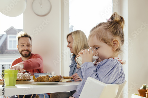 Little girl drinking milk at breakfast table