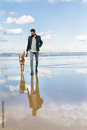 Man walking on the beach with his dog photo