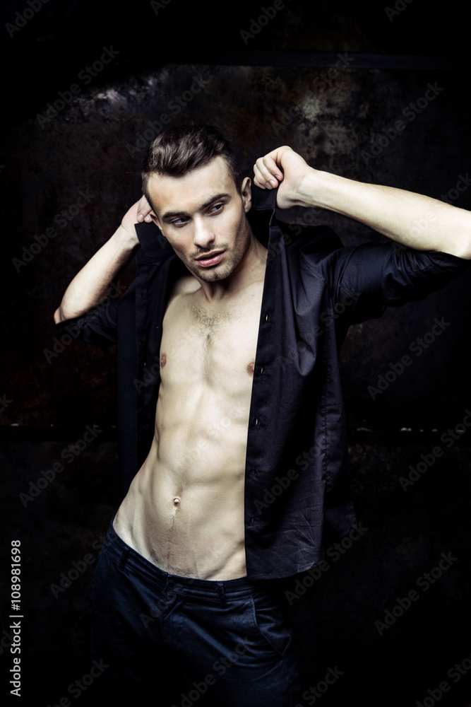 Strong Athletic Man Fitness Model Torso showing six pack abs on dark background