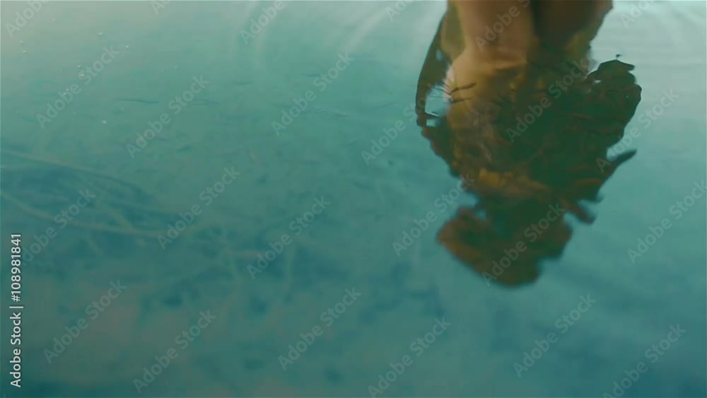 Reflection of beautiful young naked girl in the picturesque mountain lake Synevir in the Carpathians. Young nymph surrounded by  herd of little fishes. Slow motion shot Stock-Video | Adobe Stock