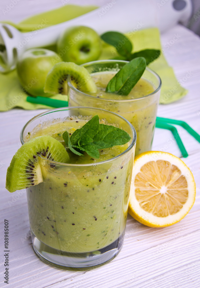 Green smoothie with mint and fruits on the wooden background Green smoothie with mint and fruits on the wooden background