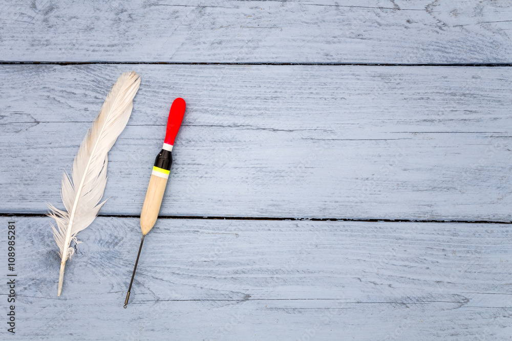 Fishing and bird feather float on the surface of the wood blue. There is a place for your labels Fishing and bird feather float on the surface of the wood blue. There is a place for your labels
