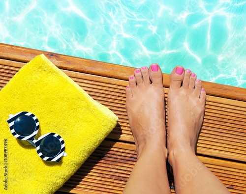 Summer holiday fashion selfie concept - woman on a wooden pier at the pool with summer accessories; sunglasses, towel