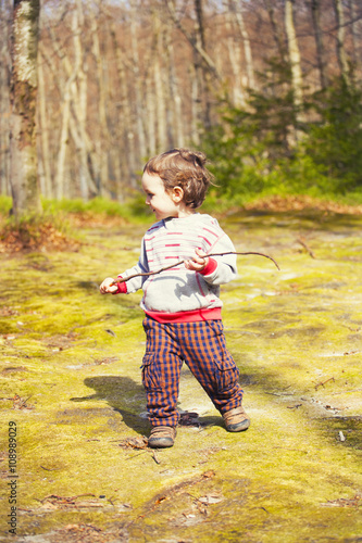 A little boy playing in the woods.